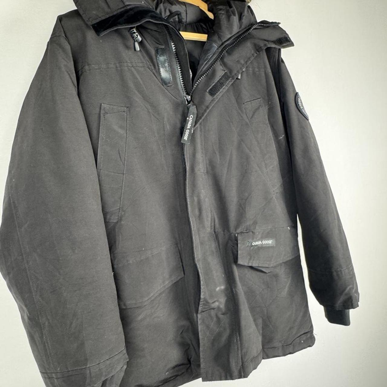 Canada Goose black parka jacket with logo patch and fur-trimmed hood.