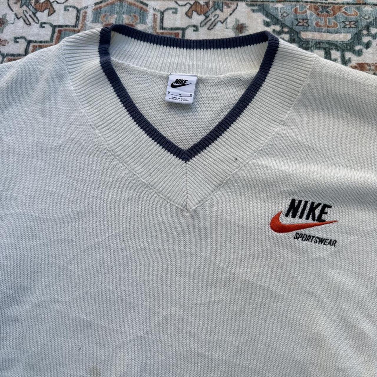 Nike cream knitted v-neck jumper with embroidered logo and visible marks on front.
