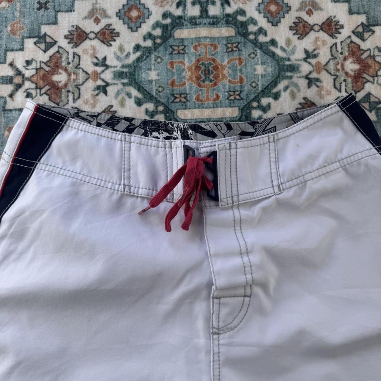 Billabong board shorts blue with embroidered Taj Burrow signature and tropical pattern.