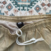 Nike ACG cream swim shorts with logo detail and lightweight material.