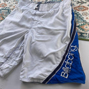 Billabong board shorts blue with tropical print and Andy Irons logo detail.