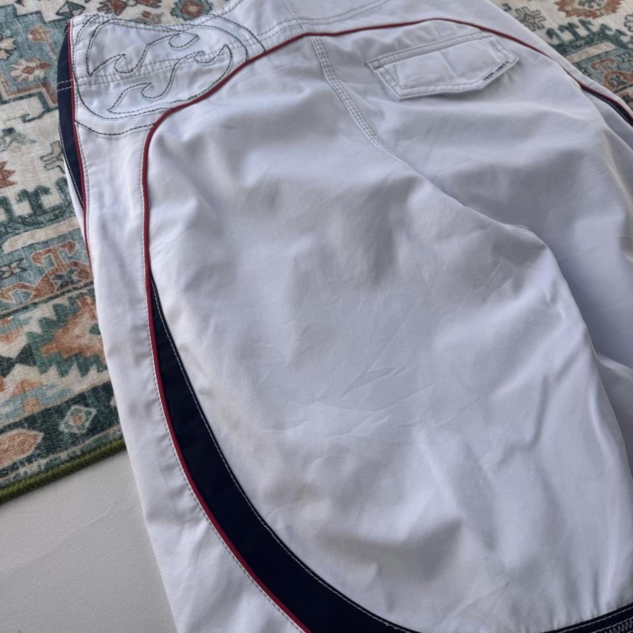 Billabong board shorts blue with embroidered Taj Burrow signature and tropical pattern.
