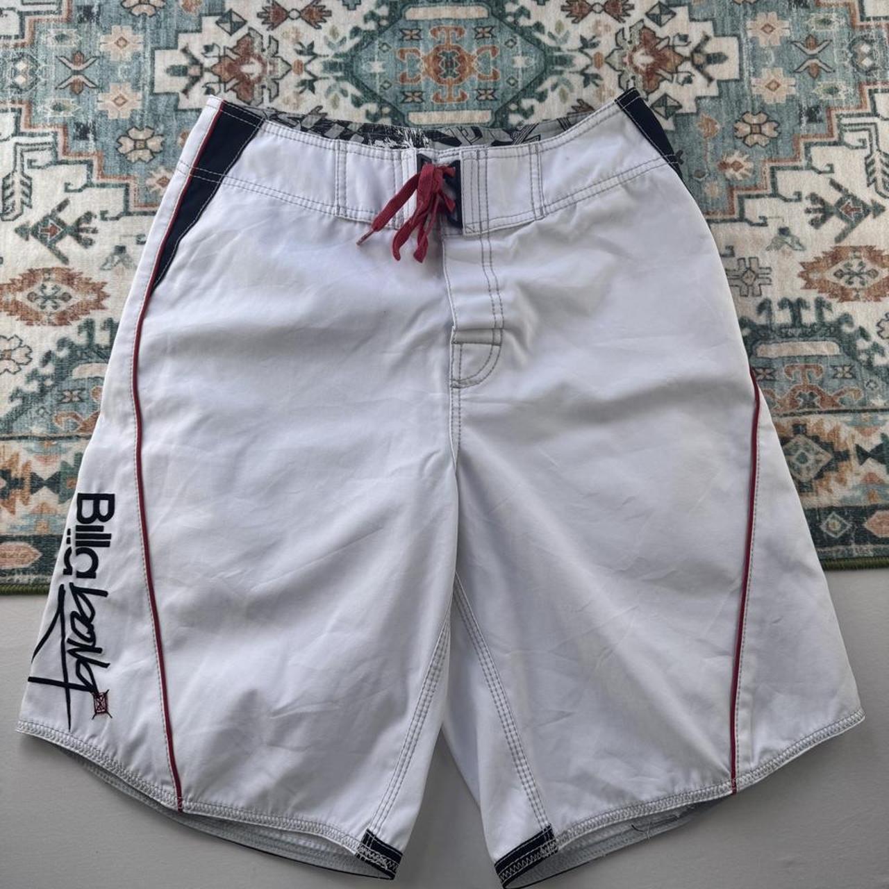 Billabong board shorts blue with embroidered Taj Burrow signature and tropical pattern.