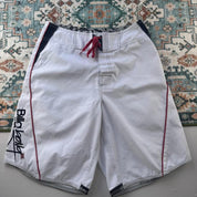 Billabong board shorts blue with embroidered Taj Burrow signature and tropical pattern.