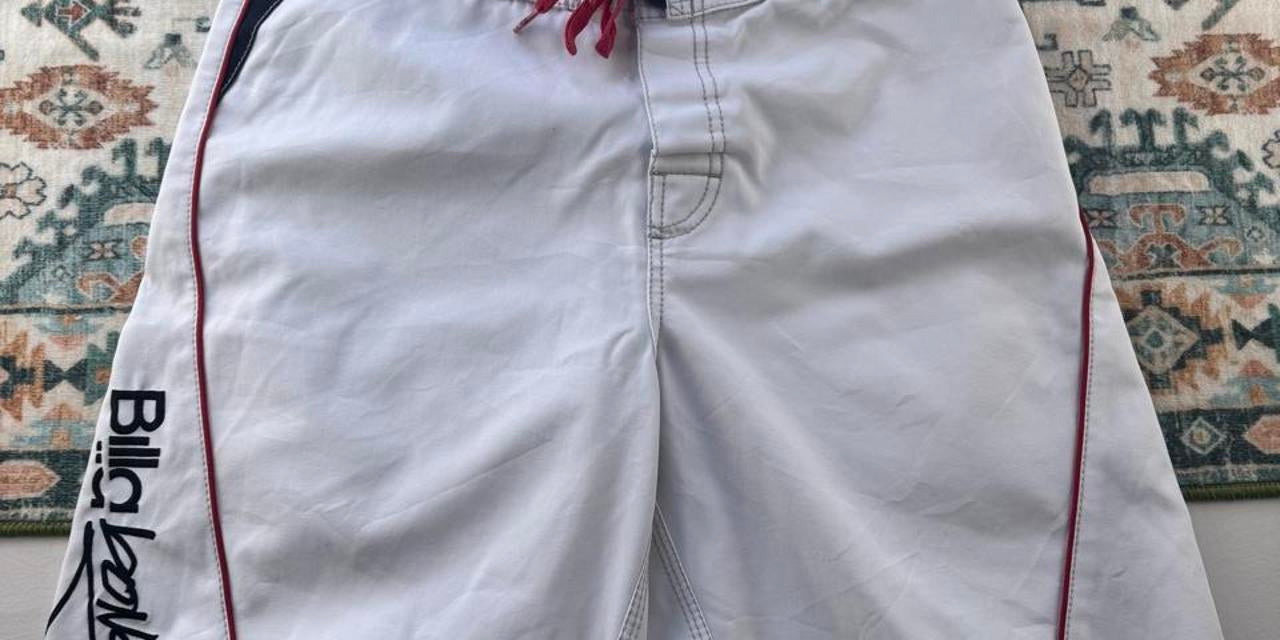 Billabong board shorts blue with embroidered Taj Burrow signature and tropical pattern.
