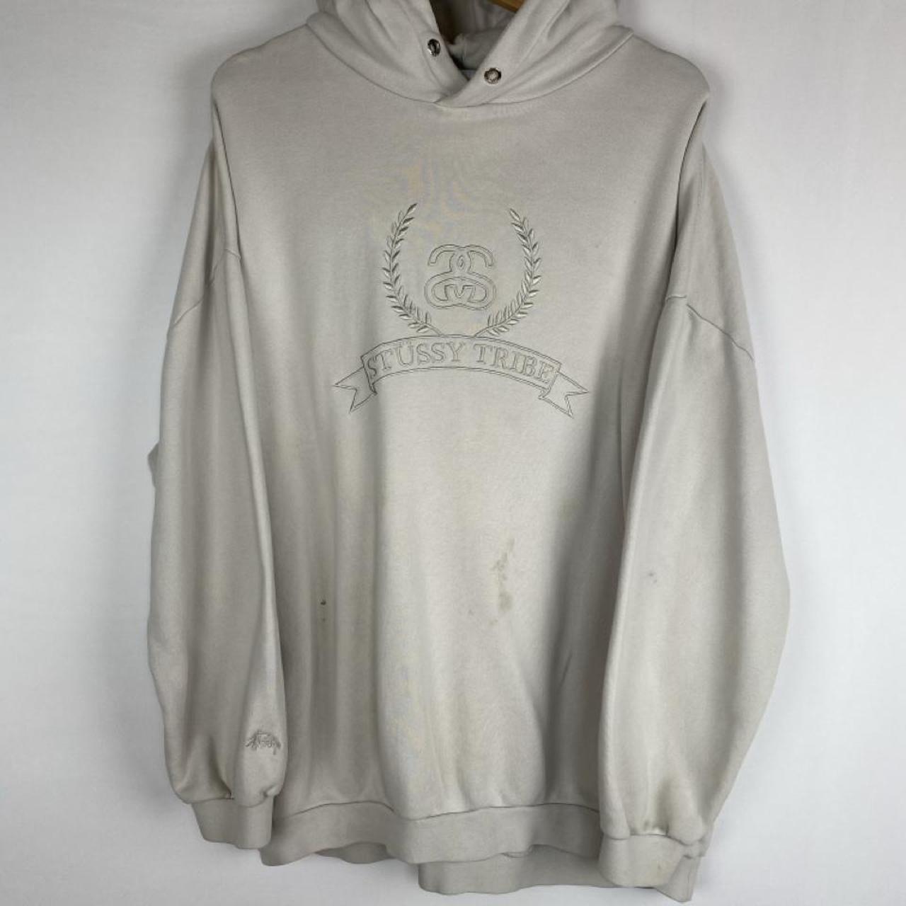 Stüssy cream hoodie with embroidered spellout logo and oversized fit.