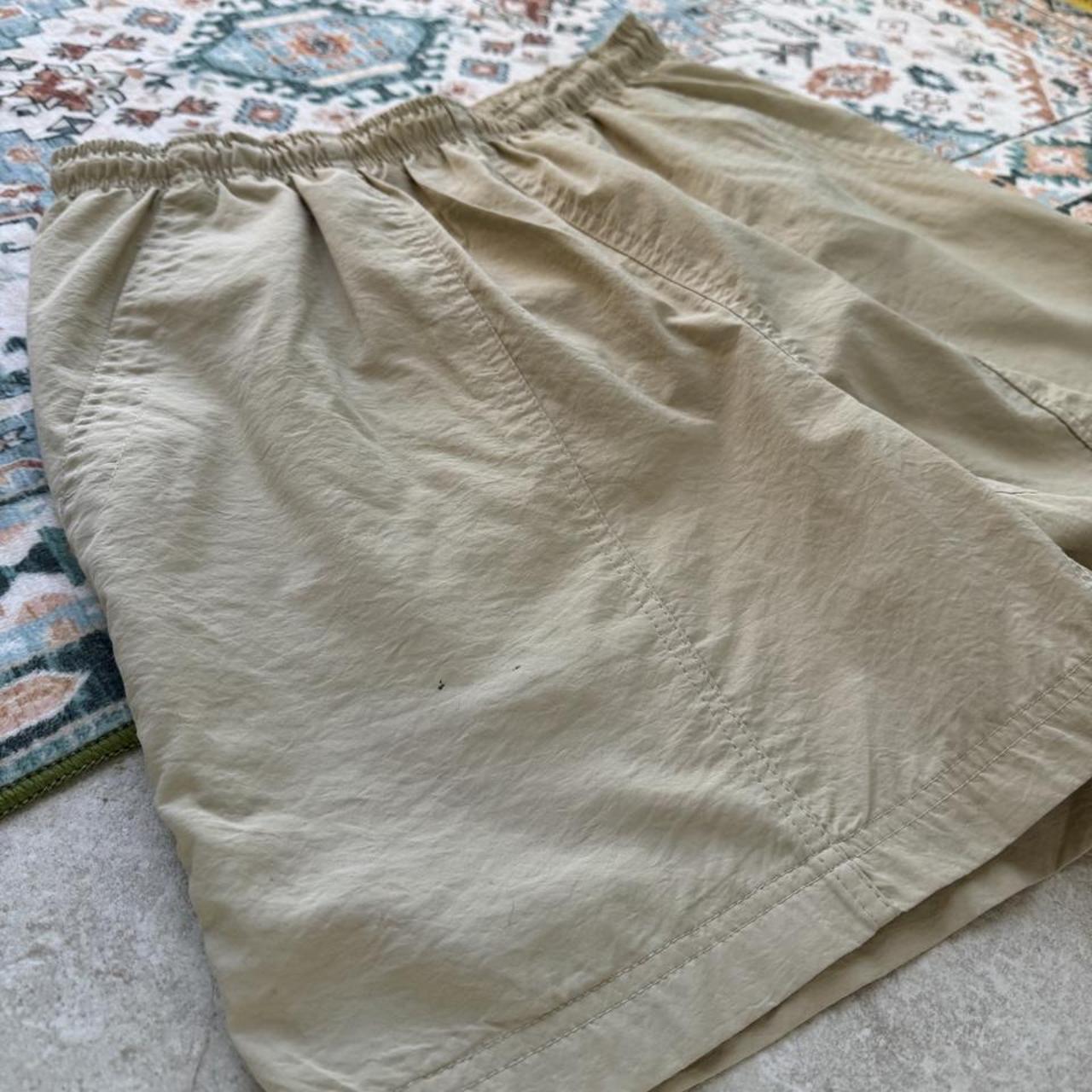 Nike ACG cream swim shorts with logo detail and lightweight material.