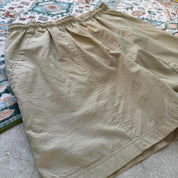 Nike ACG cream swim shorts with logo detail and lightweight material.