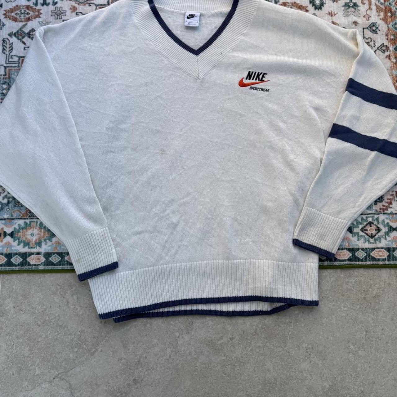 Nike cream knitted v-neck jumper with embroidered logo and visible marks on front.