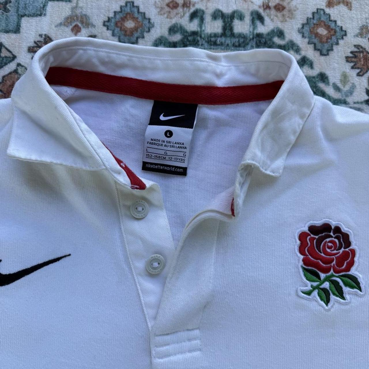 Nike black and white rugby polo shirt with England logo and striped pattern.